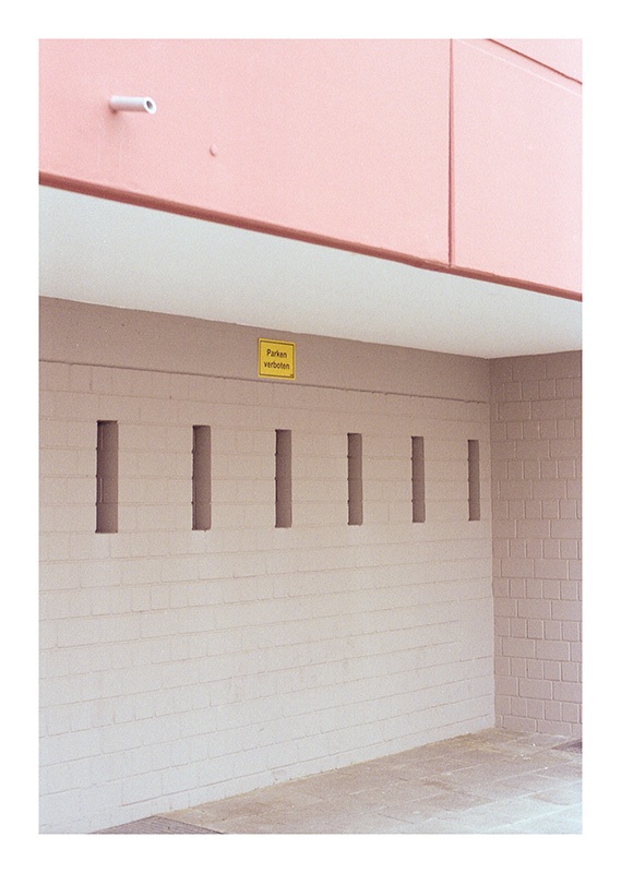 Hauswand mit rosa Balkon, gelbes Schild »Parken verboten«