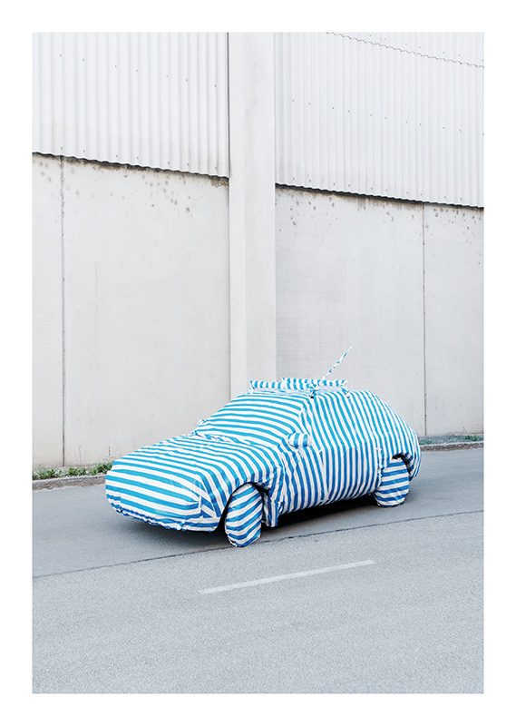 Ein Auto vor einer Wand, eingepackt in blauweißgestreiftes Geschenkpapier